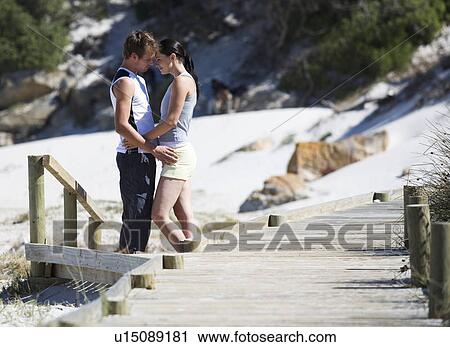 A young couple embracing on a beach View Large Photo Image Stock Image - A young couple embracing on a beach. Fotosearch