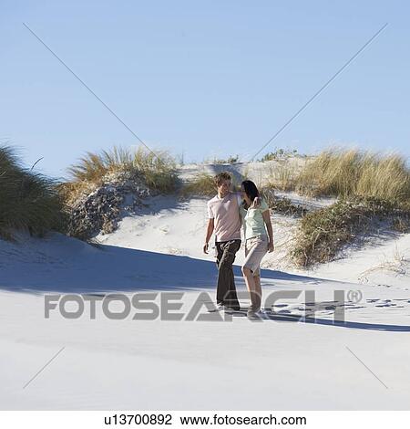 A young couple walking in sand dunes View Large Photo Image Stock Image - A young couple walking in sand dunes. Fotosearch