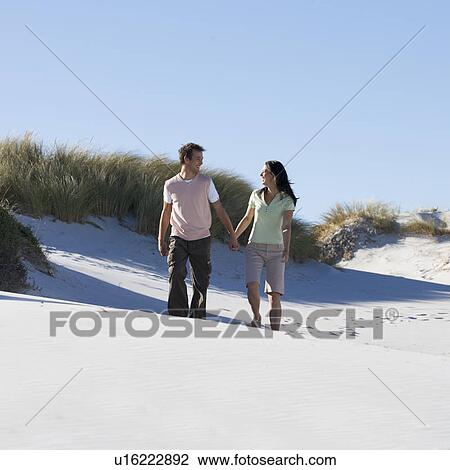 A young couple walking in sand dunes View Large Photo Image Stock Image - A young couple walking in sand dunes. Fotosearch