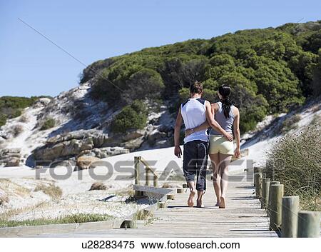 Stock Photography - A young couple walking on a beach. Fotosearch