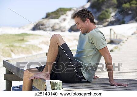 A young man sitting on a beach View Large Photo Image Stock Image - A young man sitting on a beach. Fotosearch