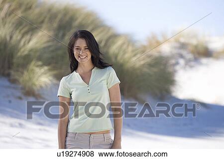 A young woman standing on a beach View Large Photo Image Stock Photo - A young woman standing on a beach. Fotosearch