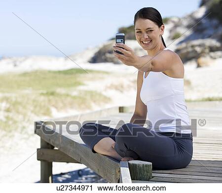 A young woman taking a photo of herself with a mobile phone View Large Photo Image Stock Image - A young woman taking a photo of herself with a mobile phone. Fotosearch