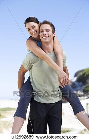 Stock Photo - Portrait of a young couple, man giving woman piggyback. Fotosearch