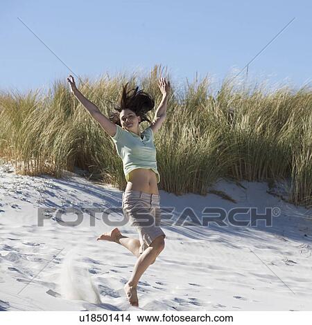 Young woman jumping in sand dunes View Large Photo Image Picture - Young woman jumping in sand dunes. Fotosearch