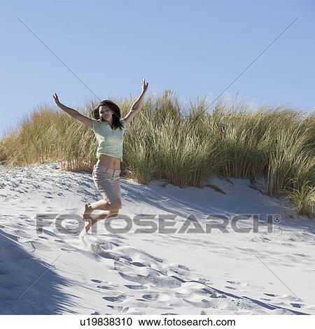 Young woman jumping in sand dunes View Large Photo Image Stock Image - Young woman jumping in sand dunes. Fotosearch