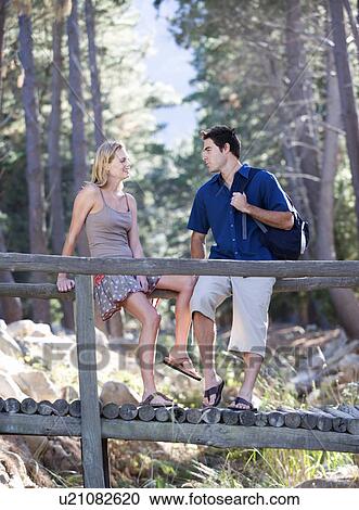A young couple standing on a wooden bridge View Large Photo Image Stock Image - A young couple standing on a wooden bridge. Fotosearch
