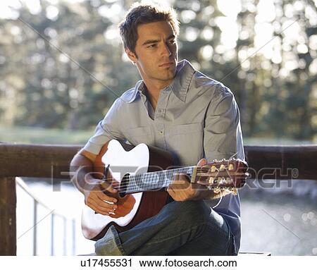 A young man playing a guitar View Large Photo Image Stock Image - A young man playing a guitar. Fotosearch