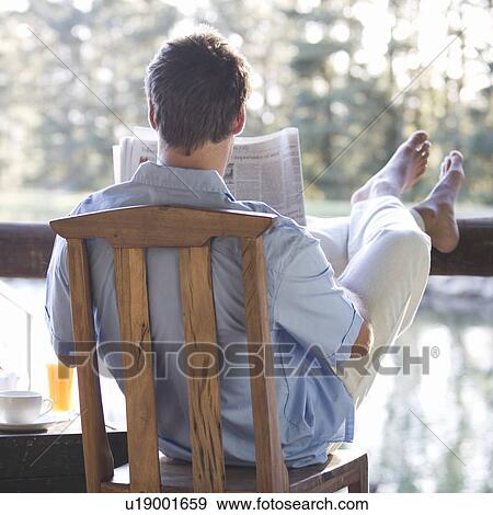 A young man reading the paper at breakfast View Large Photo Image Stock Photo - A young man reading the paper at breakfast. Fotosearch