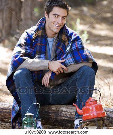 A young man sitting by a campfire View Large Photo Image Stock Photo - A young man sitting by a campfire. Fotosearch