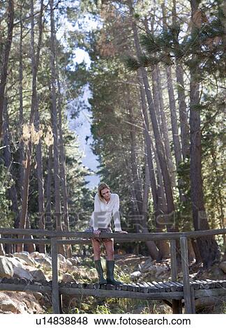 A young woman standing on a wooden bridge in a forest View Large Photo Image Stock Photo - A young woman standing on a wooden bridge in a forest. Fotosearch