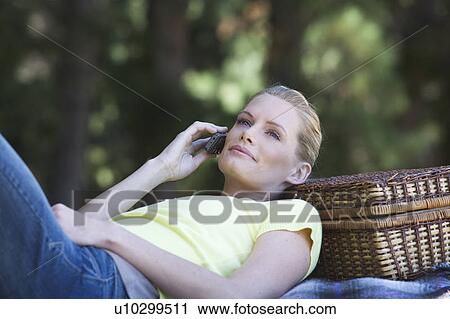 A young woman using a mobile phone at a picnic View Large Photo Image Stock Image - A young woman using a mobile phone at a picnic. Fotosearch