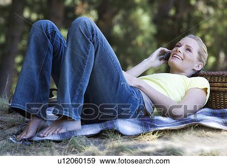 A young woman using a mobile phone at a picnic View Large Photo Image Stock Photo - A young woman using a mobile phone at a picnic. Fotosearch