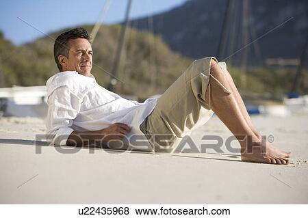 Stock Photo - A man laying on a beach. Fotosearch