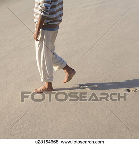 A man walking on a beach View Large Photo Image Stock Photo - A man walking on a beach. Fotosearch