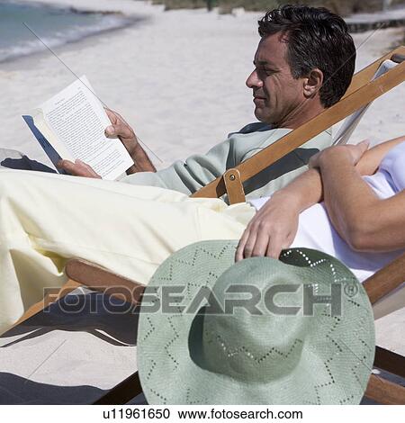 A mature couple relaxing in deckchairs on a beach View Large Photo Image Stock Image - A mature couple relaxing in deckchairs on a beach. Fotosearch