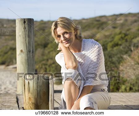 Stock Photo - A woman sitting on a beach. Fotosearch