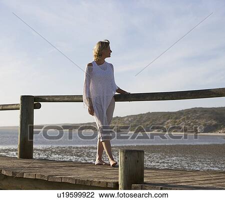 Stock Image - A woman standing on a boardwalk. Fotosearch
