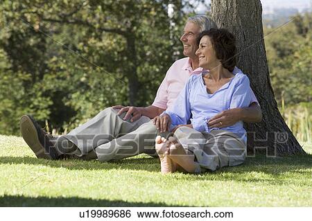 A senior couple sitting under a tree View Large Photo Image Stock Photograph - A senior couple sitting under a tree. Fotosearch