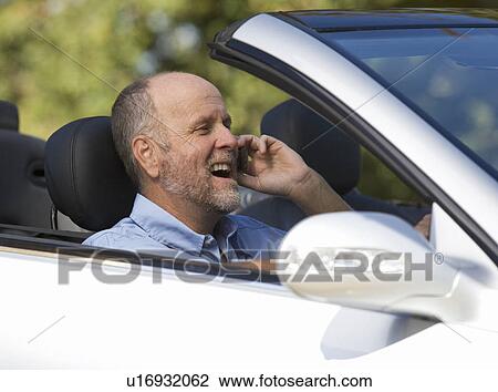 A senior man driving a car whilst on a cell phone View Large Photo Image Stock Image - A senior man driving a car whilst on a cell phone. Fotosearch
