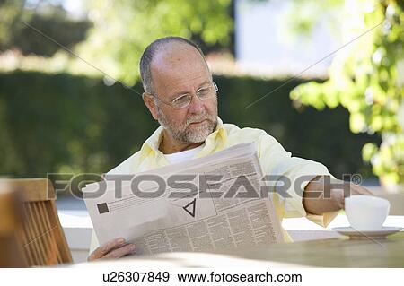 Stock Photo - A senior man reading the paper in the garden. Fotosearch