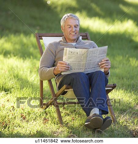 A senior man sitting in a deck chair reading a newspaper View Large Photo Image Stock Image - A senior man sitting in a deck chair reading a newspaper. Fotosearch