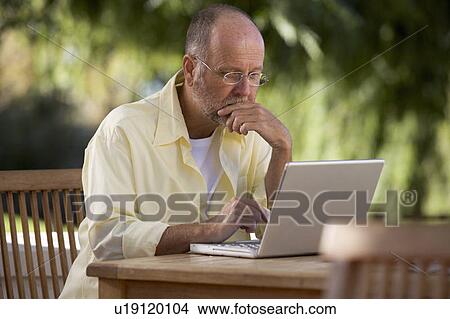 A senior man working on a laptop in the garden View Large Photo Image Picture - A senior man working on a laptop in the garden. Fotosearch