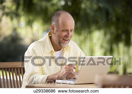 A senior man working on a laptop in the garden View Large Photo Image Stock Photograph - A senior man working on a laptop in the garden. Fotosearch
