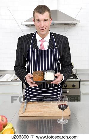 Stock Photo - Businessman preparing a meal in the kitchen. Fotosearch