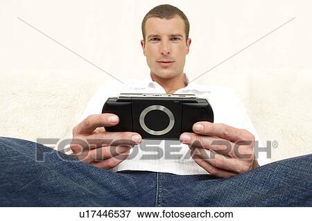 Young man holding a computer game handset View Large Photo Image Stock Photo - Young man holding a computer game handset. Fotosearch