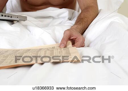 Young man in bed, reading papers, close-up View Large Photo Image Stock Image - Young man in bed, reading papers, close-up. Fotosearch