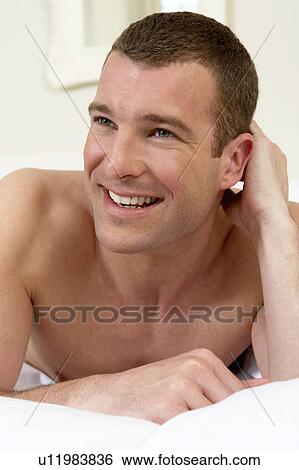 Young man in laying in bed, close-up View Large Photo Image Stock Photograph - Young man in laying in bed, close-up. Fotosearch