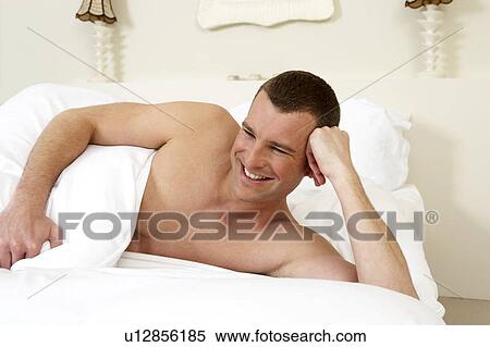 Stock Photography - Young man in laying in bed, close-up. Fotosearch