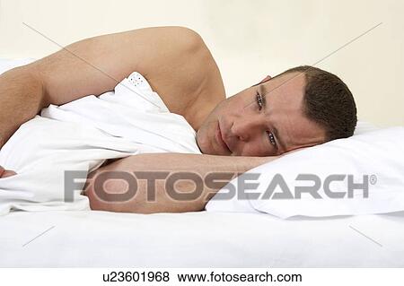 Young man laying in bed View Large Photo Image Stock Photo - Young man laying in bed. Fotosearch