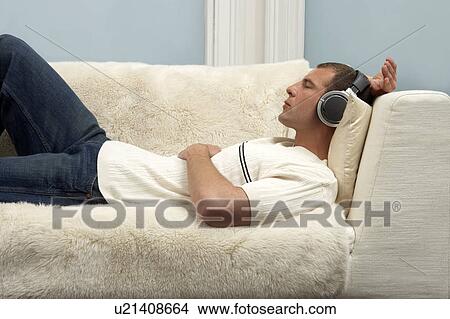 Young man listening on music through headphones View Large Photo Image Picture - Young man listening on music through headphones. Fotosearch