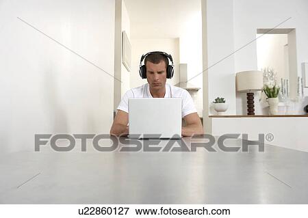 Young man working from home, listening to music View Large Photo Image Stock Photo - Young man working from home, listening to music. Fotosearch
