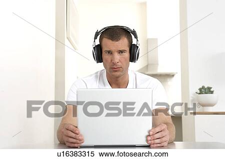 Stock Photography - Young man working from home, listening to music. Fotosearch