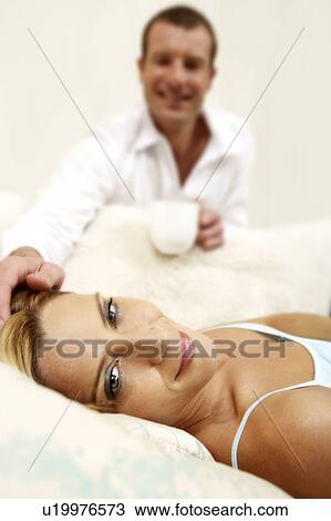 Young woman laying on a sofa watched by her partner View Large Photo Image Stock Image - Young woman laying on a sofa watched by her partner. Fotosearch