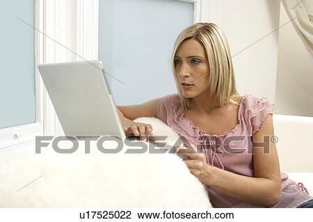 Young woman using a laptop at home View Large Photo Image Stock Image - Young woman using a laptop at home. Fotosearch