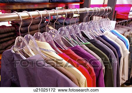 Stock Image - A stack of clothes hanging on the shelf in the store, Clothing Store. Fotosearch