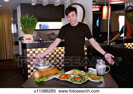 Young man standing with a table of delicious food, Restaurant View Large Photo Image Stock Photography - Young man standing with a table of delicious food, Restaurant. Fotosearch