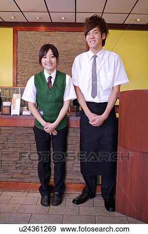 Stock Photo - Young waiter and waitress standing near the counter and smiling, Restaurant. Fotosearch