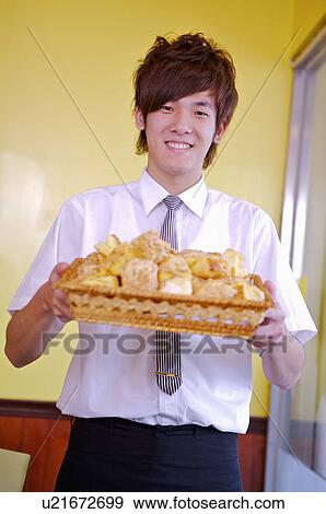 Young waiter holding a bamboo basket of cakes and smiling at the camera, Restaurant View Large Photo Image Stock Photo - Young waiter holding a bamboo basket of cakes and smiling at the camera, Restaurant. Fotosearch