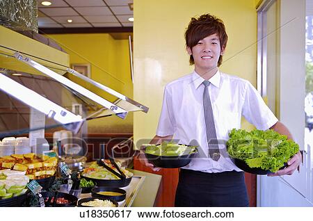 Young waiter holding vegetable and smiling at the camera, Restaurant View Large Photo Image Stock Photo - Young waiter holding vegetable and smiling at the camera, Restaurant. Fotosearch