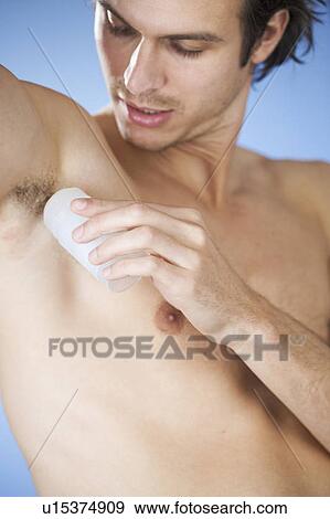 A young man applying de-odorant View Large Photo Image Stock Photo - A young man applying de-odorant. Fotosearch