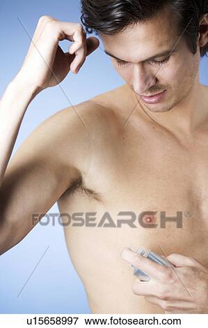 A young man applying de-odorant View Large Photo Image Stock Photo - A young man applying de-odorant. Fotosearch