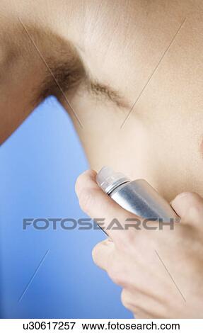 A young man applying de-odorant View Large Photo Image Stock Photo - A young man applying de-odorant. Fotosearch