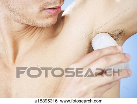Stock Photograph - A young man applying de-odorant. Fotosearch