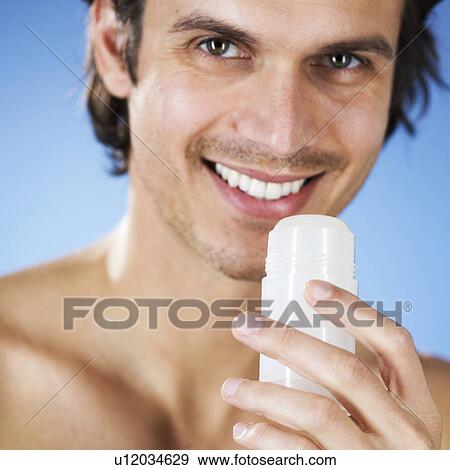 A young man holding a de-odorant stick View Large Photo Image Stock Photo - A young man holding a de-odorant stick. Fotosearch