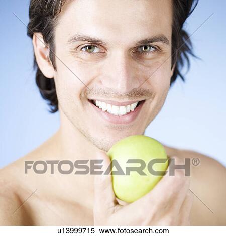 A young man holding an apple View Large Photo Image Stock Photography - A young man holding an apple. Fotosearch